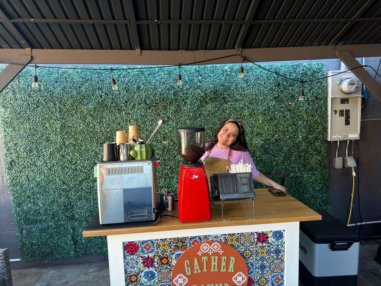Gather Round Coffee host smiling beside the mobile cart
